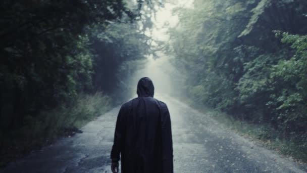 A man walking in a rain alone. He is in the way of crossing the river. 